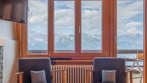 A room with two armchairs, a wooden radiator, and a TV mounted on the wall. - Bietschorn 22 by Interhome (Nendaz)