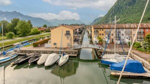A marina with boats docked, a small bridge, and buildings with a mountain backdrop. - Cook P5/3 by Interhome (Le Bouveret)
