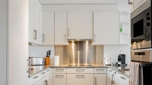 A modern kitchen with white cabinets, stainless steel appliances, and a tiled backsplash. - Cook P5/3 by Interhome (Le Bouveret)