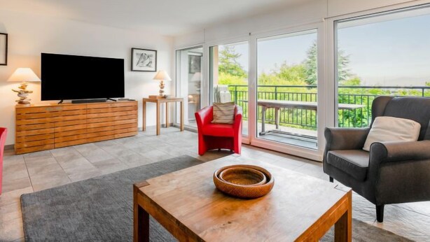 A modern living room with a television, a red chair, a grey sofa, and a wooden coffee table. - Cook P5/3 by Interhome (Le Bouveret)