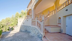 A multi-story building with a stone facade, a balcony with balustrades, and a tiled patio area. - Villa Bellevue by Interhome (Jávea)