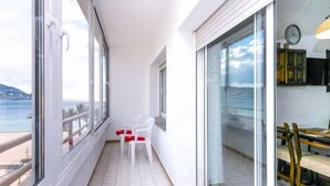 En balkon med havudsigt, hvide flisegulve og et spiseområde med stole og bord.