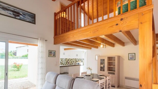 Un salon confortable avec un canapé, une table à manger et des chaises, un coin cuisine et un escalier en bois.