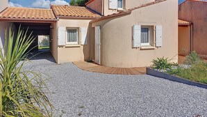 Un bâtiment à deux étages, doté d’un toit recouvert de tuiles, d’une allée en gravier et d’un petit jardin.