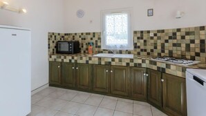Une cuisine avec des meubles en bois, un four à micro-ondes, une cuisinière à gaz et une fenêtre donnant sur un beau paysage.