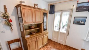 A room with a wooden cabinet, a chair, and a window with curtains. - La Busa by Interhome (Alleghe)