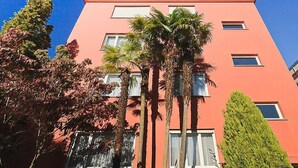 A multi-story building with a flat roof and a pink facade. - Double Room by Interhome (Ascona)