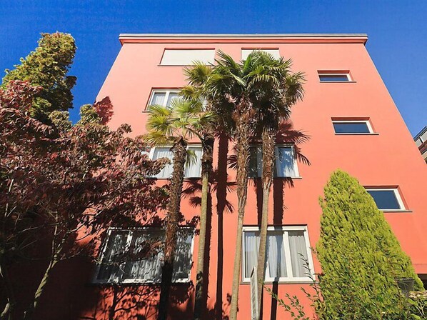 Un immeuble à plusieurs étages, doté d’un toit plat et d’une façade rose.