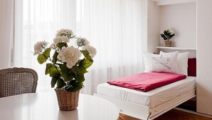 A hotel room with a bed, a dining table, and a plant. - Double Room by Interhome (Ascona)