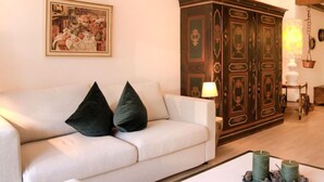A living room with a white sofa, two dark cushions, a wooden cabinet, and a painting on the wall. - Residenz Surlej 6 by Interhome (St. Moritz)