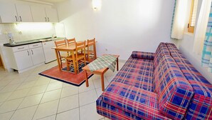 Un espace de vie compact comprenant un coin cuisine, une table à manger avec des chaises et un canapé.