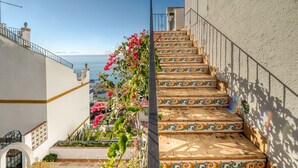 Un escalier orné de carreaux décoratifs menant à un balcon d’où l’on a vue sur la mer.