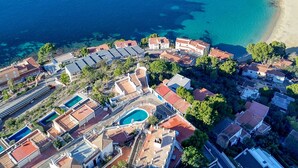 Vue aérienne d’une station balnéaire comprenant plusieurs bâtiments, des piscines et une plage.