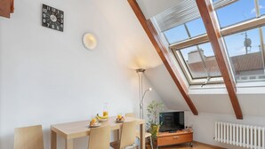 A modern loft apartment with a dining area, a TV, and a skylight. - Apartment O21 by Interhome (Prague centre)