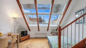 A compact room with a sloped ceiling, a wooden desk with a chair, a bed, a radiator, and a skylight. - Apartment O21 by Interhome (Prague centre)