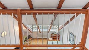 A wooden staircase with a white railing leading to an upper floor. The room below has a wooden floor, a radiator, a desk with a chair, and a television. - Apartment O21 by Interhome (Prague centre)