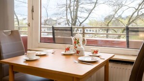 A dining table with a chair, a window with a view of trees, and a radiator. - Flora (B306) by Interhome (Lahnstein (Koblenz))