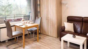 A modern room with a wooden dining table, two chairs, a brown leather sofa, a white side table, and a large wardrobe. - Flora (B306) by Interhome (Lahnstein (Koblenz))
