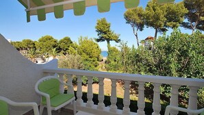 A balcony with white balustrades, green cushioned chairs, and a small table.