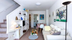 A modern living room with a staircase, a dining area, and a sofa.