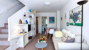 Een moderne woonkamer met een trap, een eethoek en een bank.
