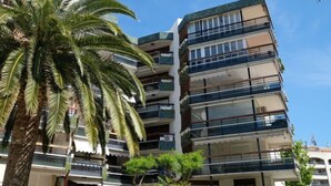 Un edificio a più piani con balconi, circondato da palme.