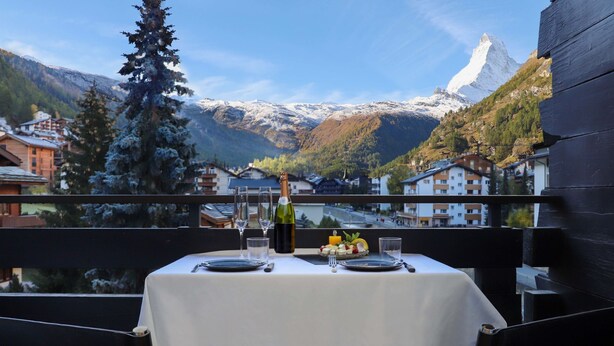 Ein Tisch für zwei Personen mit Blick auf die Berge, darunter ein schneebedeckter Gipfel, in einem Restaurant.