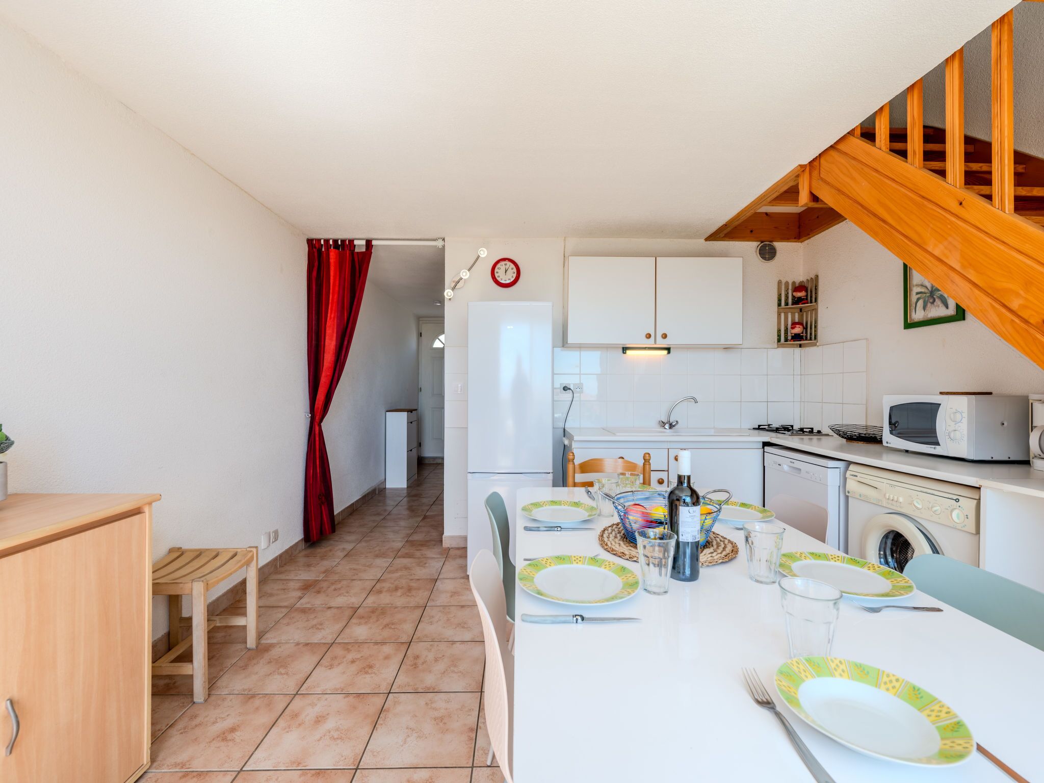 Une cuisine compacte avec des meubles blancs, un four à micro-ondes, une cuisinière et un lave-linge.