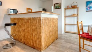 A modern kitchen with a bamboo-textured island, a microwave, and a wooden shelf. - Picasso by Interhome (Lacanau)