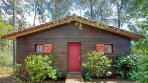 A rustic cabin with a red door, wooden siding, and a small porch. - Picasso by Interhome (Lacanau)