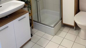 Un bagno con cabina doccia, lavandino, WC e armadietto.