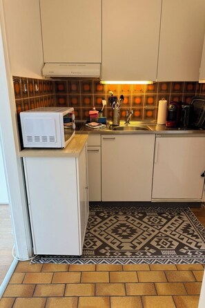 A compact kitchen with a microwave, sink, and various kitchen utensils. - Residenza Corallo by Interhome (Ascona)