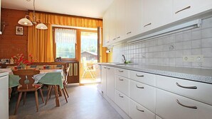 A kitchen with white cabinets, a tiled backsplash, and a dining area with a table and chairs.
