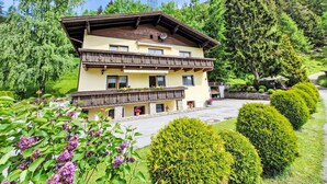 A two-story building with a balcony, surrounded by well-maintained gardens and trees.