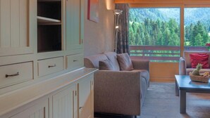A cozy living room with a sofa, a table with a basket, and a view of a forest through large windows. - Rosablanche C51 by Interhome (Siviez-Nendaz)