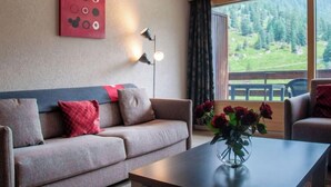 A modern living room with a sofa, a coffee table, and a view of a mountainous landscape through large windows. - Rosablanche C51 by Interhome (Siviez-Nendaz)