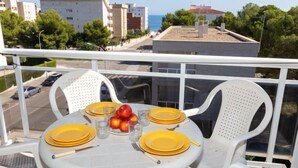 Ein Balkon mit Tisch für zwei Personen, ausgestattet mit gelben Tellern, Besteck und einer Obstschale.