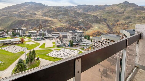 A modern building complex with multiple structures, a central courtyard, and a mountainous backdrop. - Pelvoux 102 by Interhome (Les Menuires)