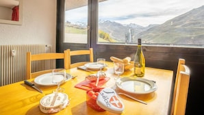 A dining table set with plates, cutlery, a bottle of wine, and a bowl of fruit. - Pelvoux 102 by Interhome (Les Menuires)