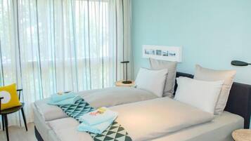 Une chambre d’hôtel avec un lit, une chaise, une table de chevet et une lampe fixée au mur.