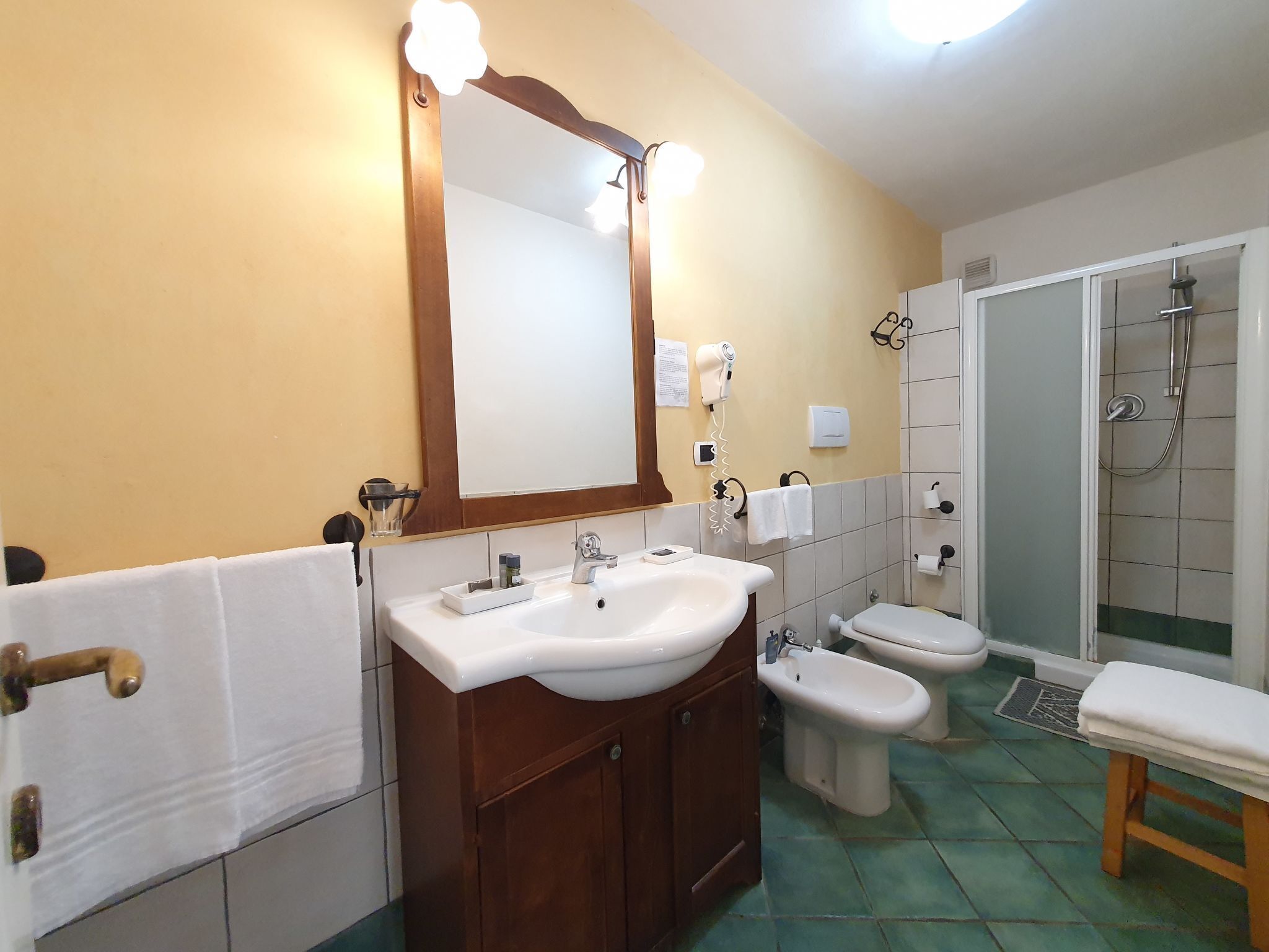 A bathroom with a sink, mirror, towel rack, and shower.