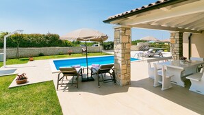 A covered outdoor area with a pool, lounge chairs, and umbrellas. - Vacation home Angela by Interhome (Poreč/Sv. Lovreč)