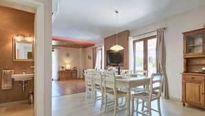 A dining area with a white table and chairs, a chandelier, and a television on the wall. - Vacation home Angela by Interhome (Poreč/Sv. Lovreč)
