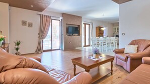 A spacious living room with leather sofas, a wooden coffee table, and a dining area with white chairs and a table. - Vacation home Angela by Interhome (Poreč/Sv. Lovreč)