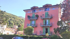 Un immeuble à plusieurs étages doté de balcons, d’une aire de stationnement et d’une colline en arrière-plan.