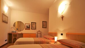 Une chambre d’hôtel avec deux lits, un bureau, une chaise, une commode et un miroir fixé au mur.