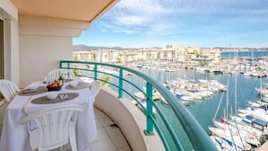 Un balcone con un tavolo apparecchiato per mangiare, con vista su una marina che include barche e edifici sullo sfondo.