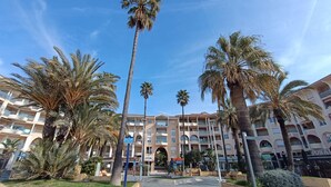 Un hotel con un cortile centrale, palme e un edificio con numerosi balconi.