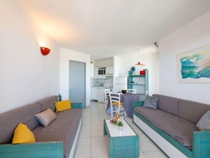 Uma sala de estar moderna com dois sofás, uma mesa de centro e um espaço de jantar com cadeiras e uma mesa.
