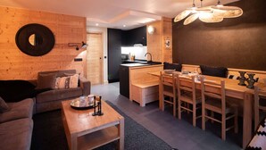 A modern living room with a wooden sofa, a coffee table, and a dining area with a wooden table and chairs. - 5-room duplex for 10 guests with balcony, Hameau de la Forêt (Valmorel)